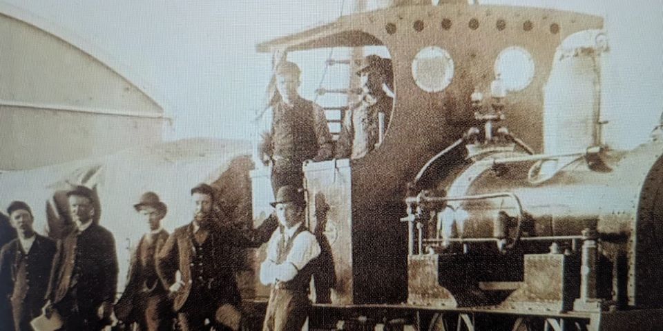 men standing by old train engine